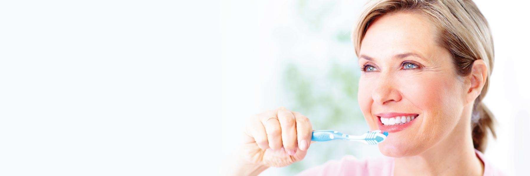 A smiling woman brushing her teeth