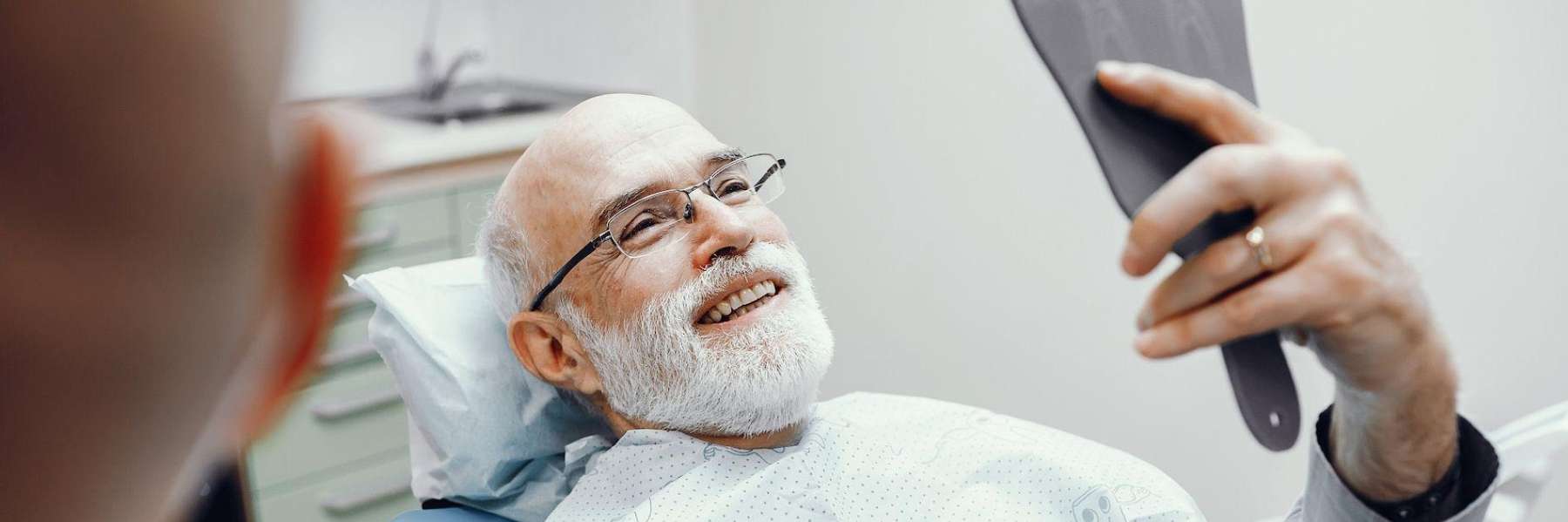 A smiling man looking at his cosmetic dental work