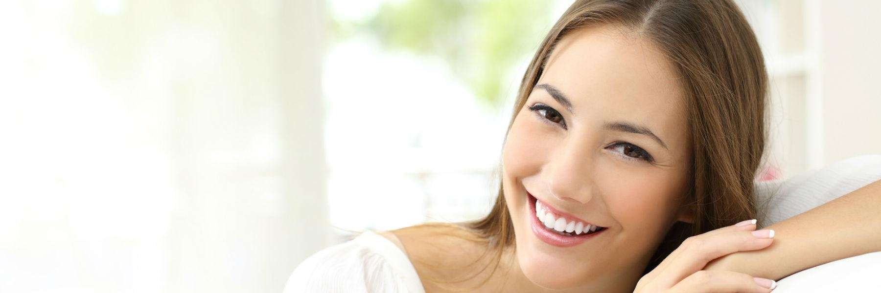 A smiling woman on the couch | dentist long beach ca