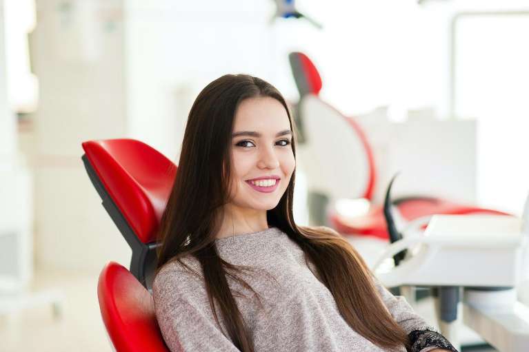 A smiling woman getting a dental exam in Long Beach