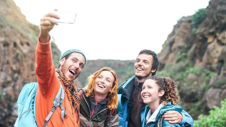 A group of friends capturing a selfie in the mountains, highlighting their excitement.