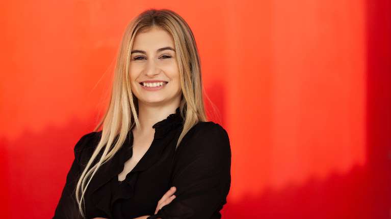 A smiling woman with an orange background | Long beach dental crowns
