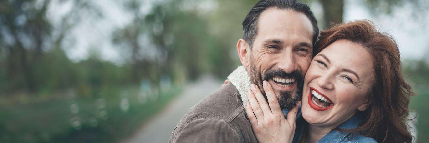 A laughing couple in the park | tooth extraction Long Beach