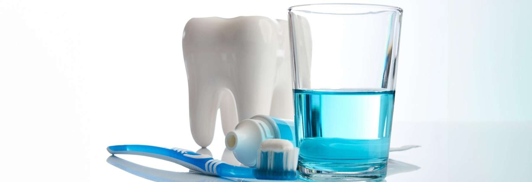 A tooth with a toothbrush, toothpaste and cup of water