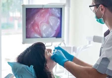 A dentist using an intraoral camera on a patient
